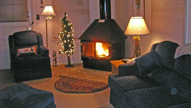Ein gemütliches Wohnzimmer mit Kamin, Weihnachtsbaum und zwei Lampen.