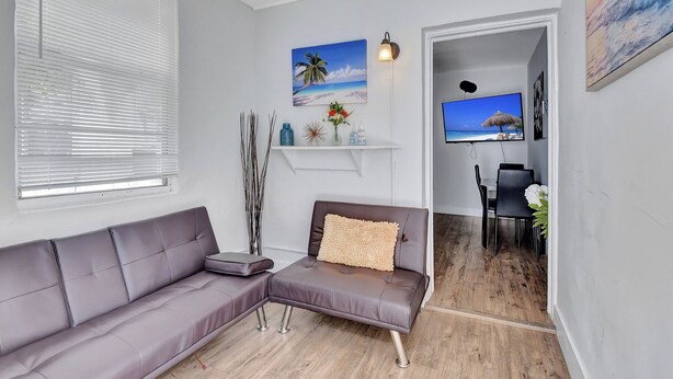 Una sala de estar moderna con un sofá seccional, una mesita auxiliar, un estante decorativo y un televisor de pantalla plana montado en la pared.