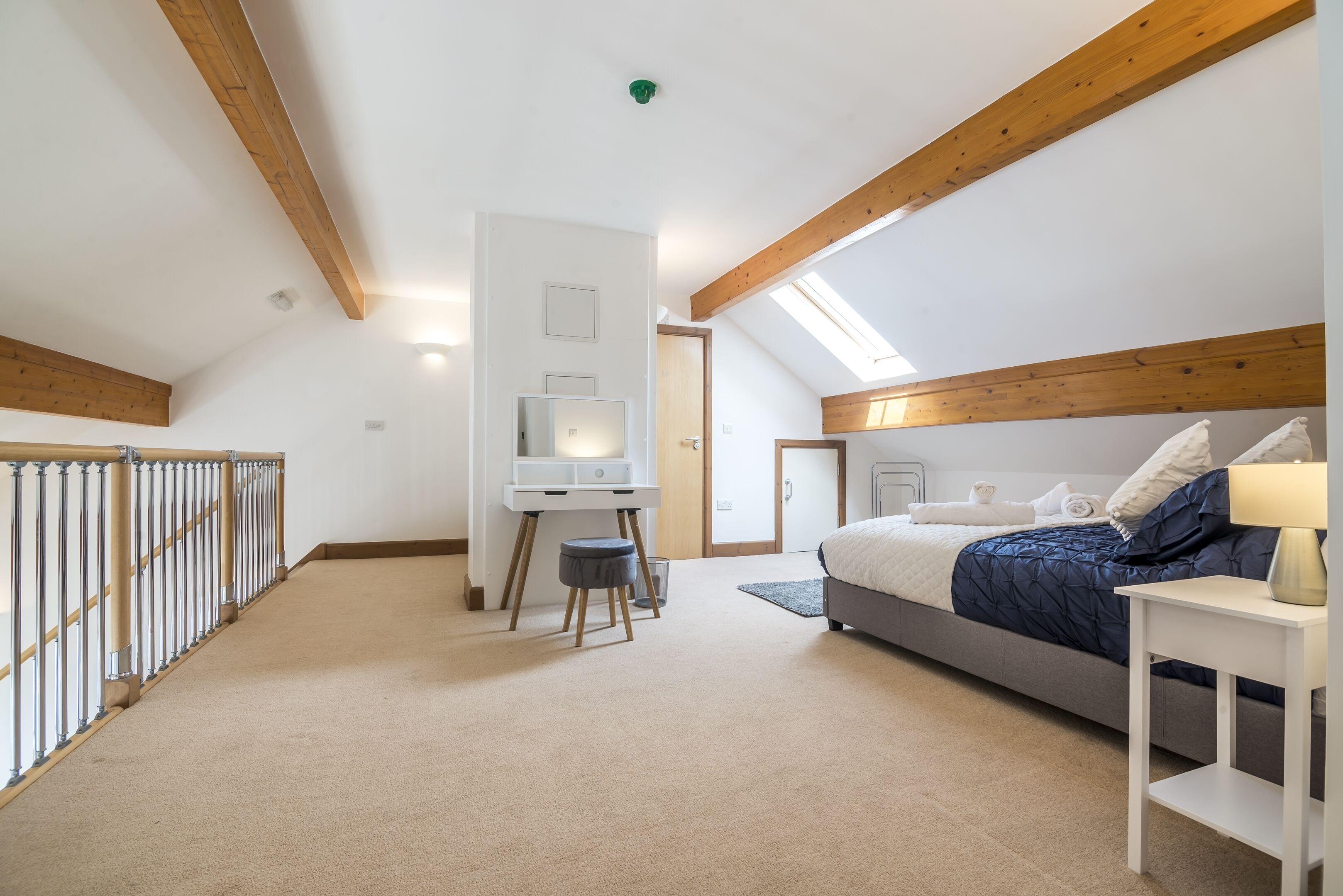 A bedroom with a bed, desk, and a skylight.