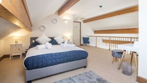 A bedroom with a large bed, bedside tables, a desk, and a chair.