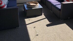 Un área de estar al aire libre techada, con mobiliario de mimbre y una mesa de centro trenzada.