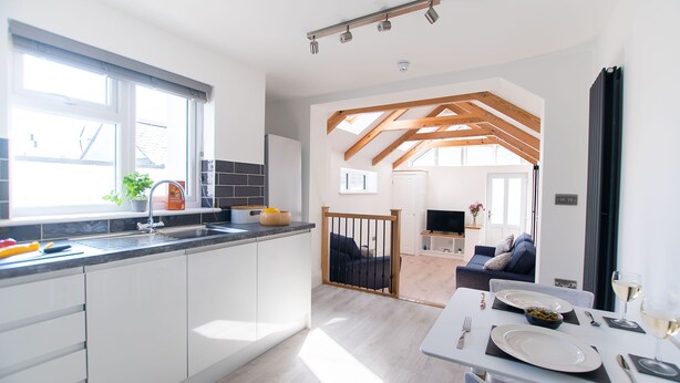 A modern kitchen with white cabinets, a large window, and a dining area with a table set for two.