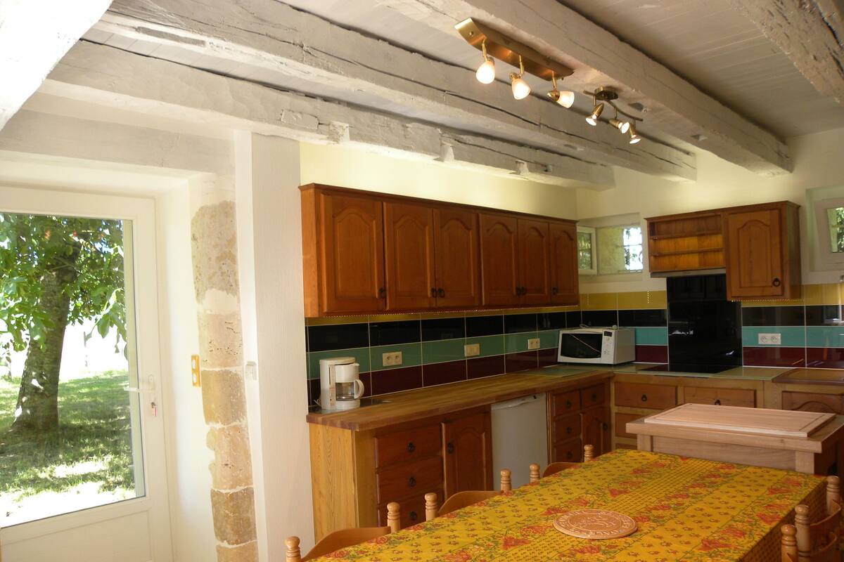 A kitchen with wooden cabinets, a microwave, and a dining table with a floral tablecloth.