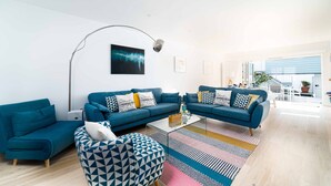 A modern living room with two blue sofas, a coffee table, and patterned cushions.