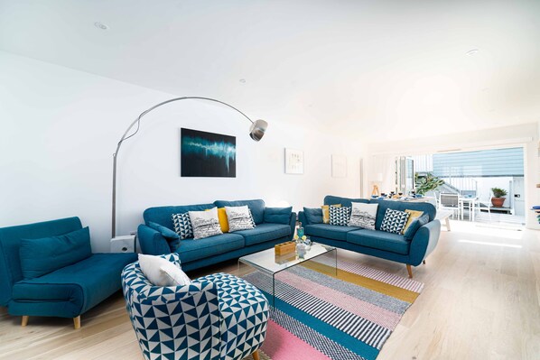 Ein modernes Wohnzimmer mit zwei blauen Sofas, einem Couchtisch und gemusterten Kissen.