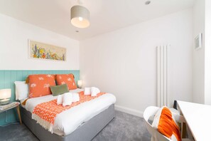 Ein ordentlich eingerichtetes Schlafzimmer mit Bett, Nachttisch und Schreibtisch.