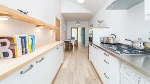 A modern kitchen with white cabinets, a wooden countertop, and a Bosch dishwasher.