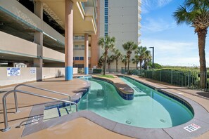 A swimming pool with a no lifeguard sign, a parking garage, and palm trees. - Verandas 405 - 3 Bedrooms of Ocean Front Beautiful - Pool & Lazy River (North Myrtle Beach)