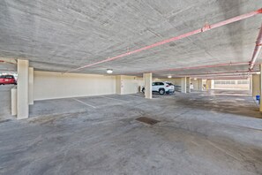 An underground parking garage with concrete floors and walls, red pipes on the ceiling, and a few cars parked. - Verandas 405 - 3 Bedrooms of Ocean Front Beautiful - Pool & Lazy River (North Myrtle Beach)