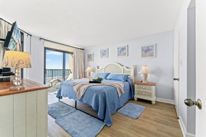Ein Schlafzimmer mit Bett, Nachttischen, Fenster und Tür.