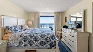 Una habitación de hotel con una cama grande, televisión, cómoda y vistas al océano.