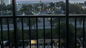 Ein Balkon mit Blick auf einen Sonnenuntergang über dem Meer, ein Schwimmbecken und ein Parkplatz.