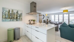 Eine moderne Küche mit weißen Schränken, einer Edelstahl-Dunstabzugshaube und einem Stadtbild an der Wand.