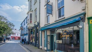 A street view with a restaurant named 'On George's' and a shop with a sign 'White Fish'. - Tipyn O Haul - 1 Bedroom Apartment - Tenby (Tenby)