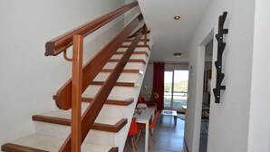 Un escalier avec des rampes en bois mène à un espace repas comprenant une table et des chaises.