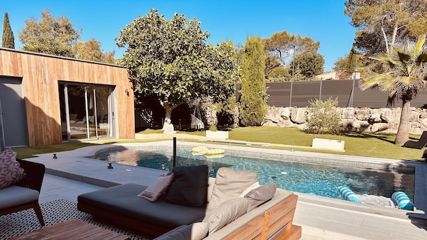 A modern outdoor pool area with a wooden deck, a lounge chair, and a sofa.