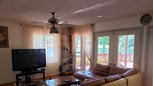 Una sala de estar con sofá, televisión y ventilador de techo.