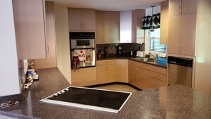 Una cocina moderna con encimera de granito, electrodomésticos de acero inoxidable y armarios de madera clara.