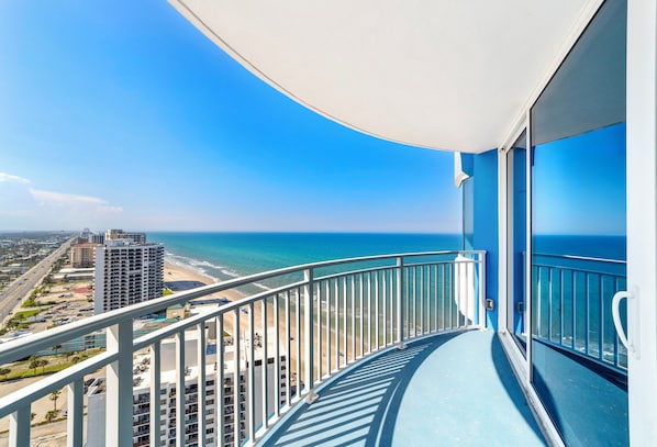 A balcony with a view of the ocean and a cityscape.