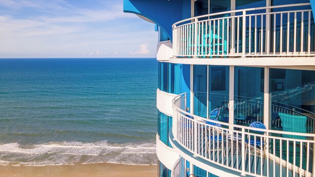 A multi-level building with balconies overlooking a beach and ocean.