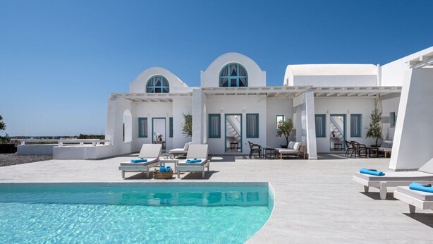 Un resort moderno con piscina, arquitectura blanca y zonas de estar al aire libre.