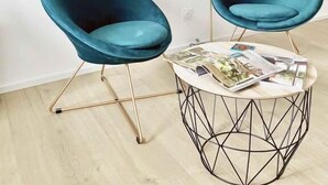A room with two teal chairs, a round table with magazines, and three framed pictures on the wall. - Your modern retreat in the heart of Rochefort - A unique experience (Rochefort)