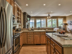 A spacious kitchen with wooden cabinets, a stainless steel refrigerator, and a large island.