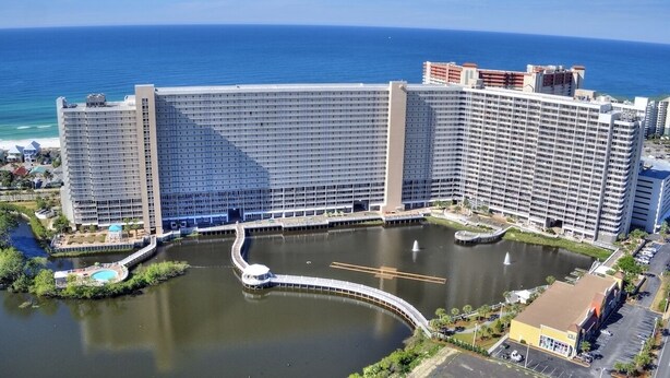 A large hotel with multiple floors, a central courtyard with a fountain, and a view of the ocean.