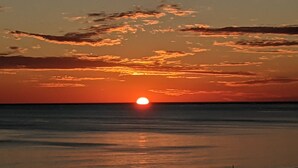 A sunset over the ocean with clouds in the sky.
