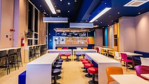 Un café moderno con una barra larga, varios taburetes y mesas.