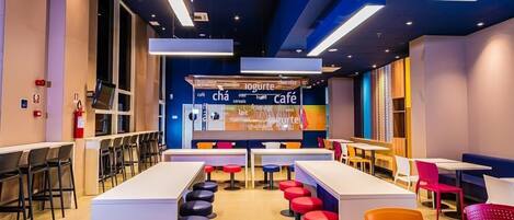 Un café moderno con una barra larga, varios taburetes y mesas.