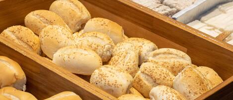 Una exhibición de pan de madera con bollos de sésamo y otras variedades.