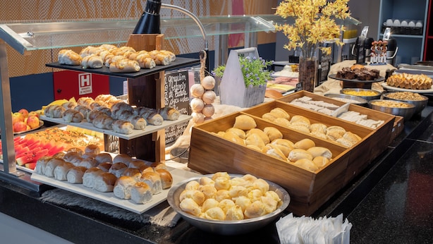 Mostrador de panadería con una variedad de productos horneados, como pasteles y pan, organizados en estantes y recipientes.