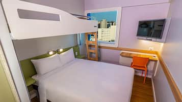 Una cama litera con escritorio y silla, un televisor y una ventana con vistas a la ciudad.