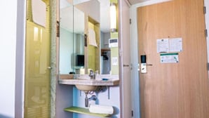 Un baño pequeño con lavamanos, espejo y puerta de madera.