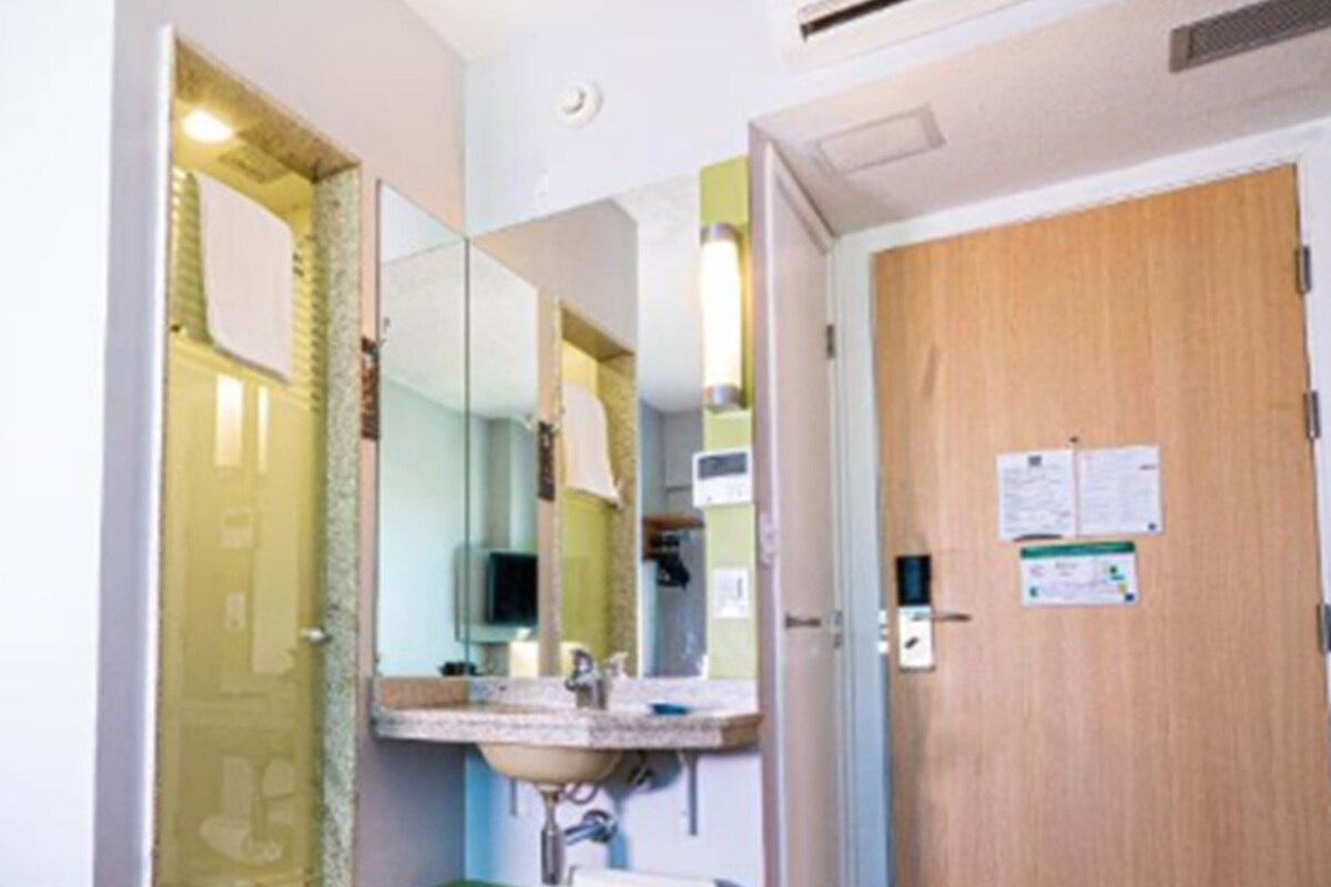 A small bathroom with a sink, mirror, and a wooden door.