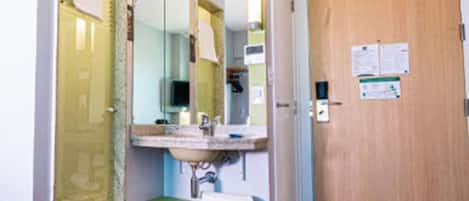 A small bathroom with a sink, mirror, and a wooden door.