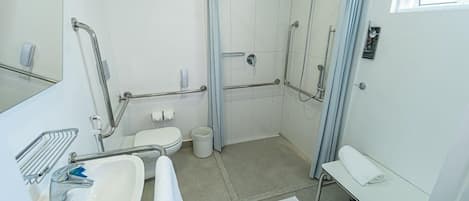 Un baño moderno con ducha, inodoro, lavabo y un banco.