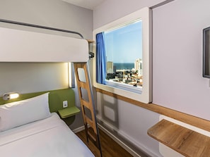 Ein Stockbett mit Blick auf eine Stadtlandschaft durch ein Fenster.