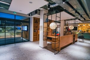 Un intérieur moderne comprenant un comptoir d’accueil, des étagères en bois et un espace bar.