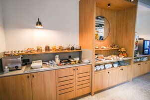 Un buffet de petit-déjeuner proposant une variété d’aliments et de boissons, des meubles en bois et un miroir au mur.