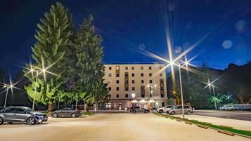 Un hôtel à la façade moderne, doté d’un parking et de lampadaires.