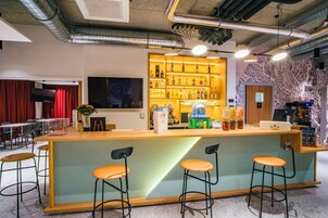 Un espace bar avec un comptoir, des tabourets, un téléviseur et une étagère remplie de bouteilles.