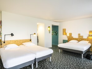 A hotel room with two beds, a checkered floor, and a wall-mounted lamp.