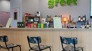 Uma área de bar com um letreiro que diz 'greet', um quadro de menu e diversos frascos e copos nas prateleiras.