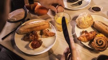 A breakfast setting with bread, croissants, and a glass of orange juice on a table.