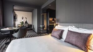 A modern hotel room with a large bed, a desk with a chair, and a small table with a lamp. - ibis Styles Arnhem Centre (Arnhem)