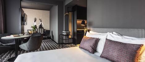 Una habitación de hotel moderna con una cama grande, un escritorio con una silla y una mesita con una lámpara.