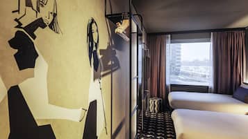 Een hotelkamer met een stapelbed, een groot raam met gordijnen en een muurschildering.