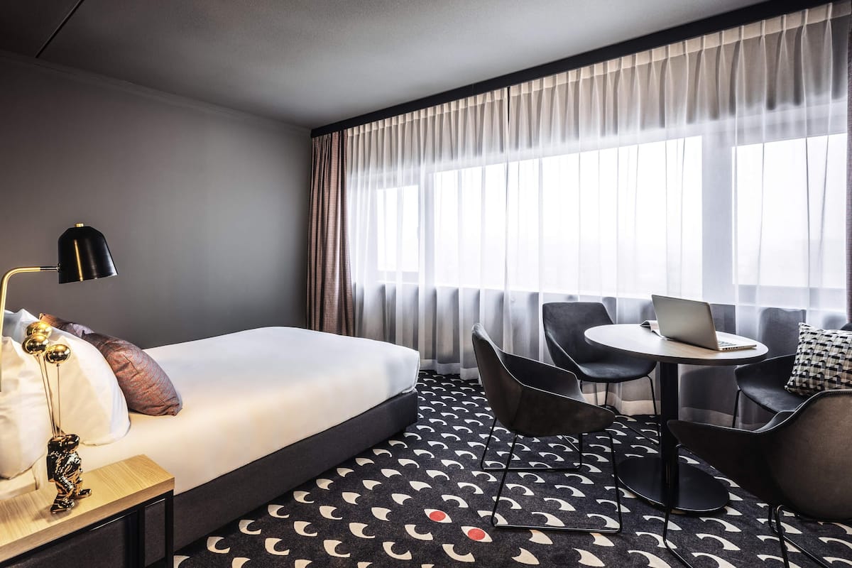 Una habitación de hotel con una cama, un escritorio, una computadora portátil y una silla.